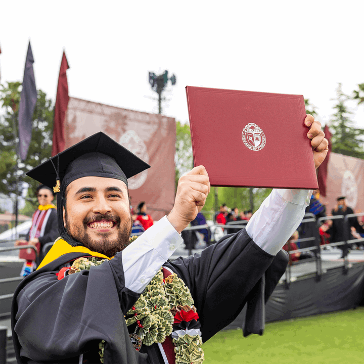 U of R Graduate proudly holding up diploma